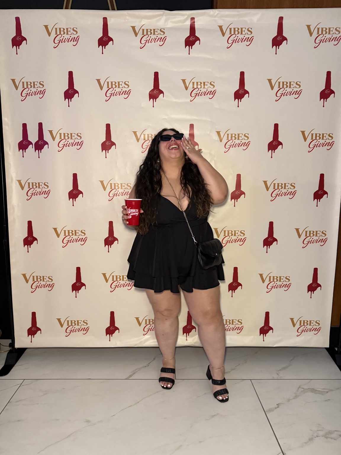 Guest posing in front of the Vibesgiving branded backdrop